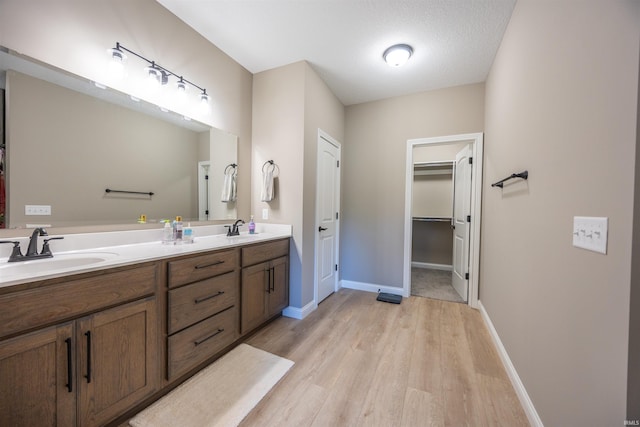 bathroom featuring a sink, double vanity, baseboards, and wood finished floors