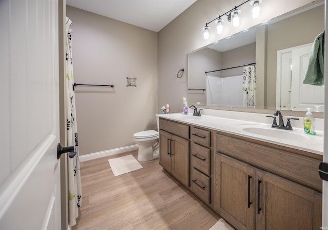 bathroom with toilet, double vanity, a sink, and wood finished floors