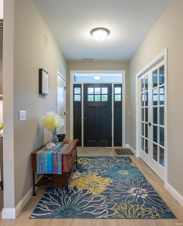 entrance foyer featuring baseboards, visible vents, and a textured ceiling
