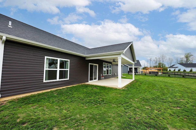 back of property with a patio, fence, a lawn, ceiling fan, and roof with shingles