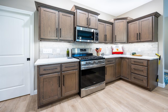 kitchen featuring backsplash, appliances with stainless steel finishes, baseboards, and light wood-type flooring