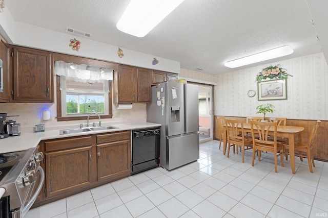 kitchen featuring a sink, a textured ceiling, visible vents, wallpapered walls, and appliances with stainless steel finishes