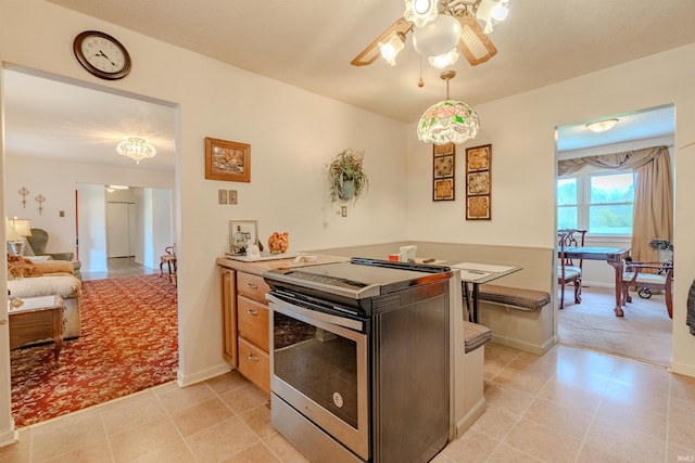 1112 W Walnut St, Summitville, IN 46070 - kitchen with a peninsula, stainless steel range with electric stovetop, baseboards, ceiling fan, and light countertops