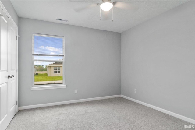 empty room with carpet, baseboards, a ceiling fan, and visible vents