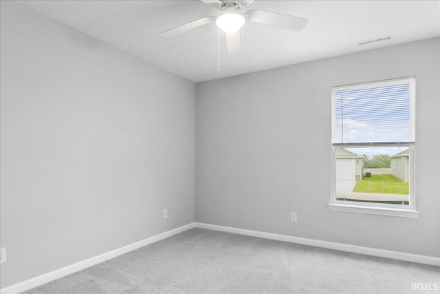 carpeted spare room featuring baseboards, ceiling fan, and visible vents