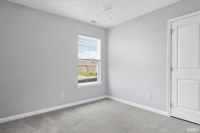 carpeted spare room featuring baseboards, visible vents, and a ceiling fan