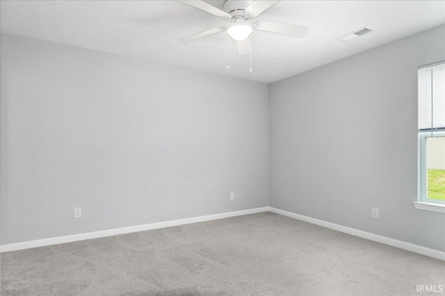 carpeted spare room with a ceiling fan, baseboards, and visible vents