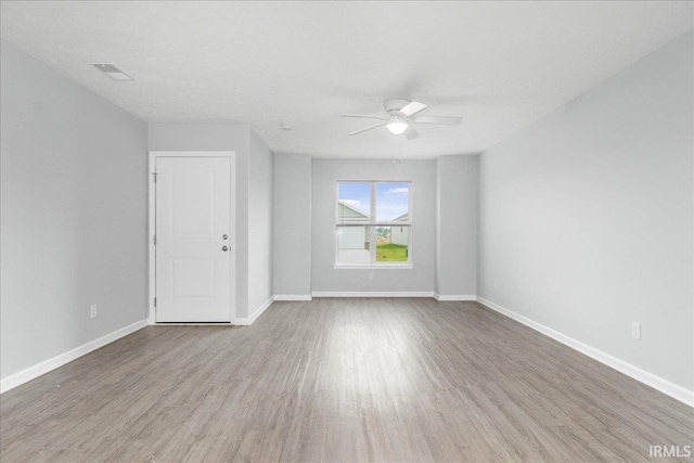 spare room with visible vents, wood finished floors, baseboards, and ceiling fan