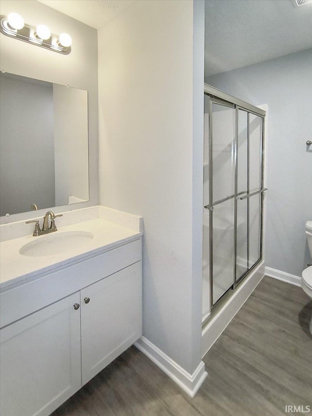 full bath with toilet, baseboards, a shower stall, and wood finished floors