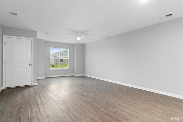 empty room featuring visible vents, wood finished floors, baseboards, and ceiling fan