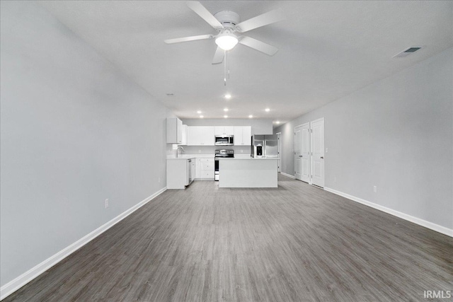 unfurnished living room featuring visible vents, baseboards, ceiling fan, and dark wood-style floors