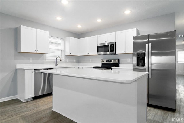 kitchen featuring stainless steel appliances, dark wood finished floors, light countertops, a center island, and white cabinets