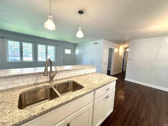 kitchen featuring white cabinetry, ornamental molding, a sink, and decorative light fixtures