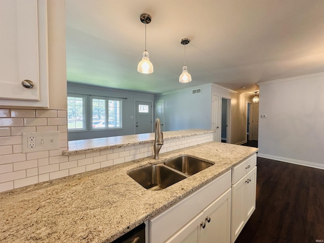 kitchen with a sink, ornamental molding, light stone counters, white cabinetry, and decorative backsplash