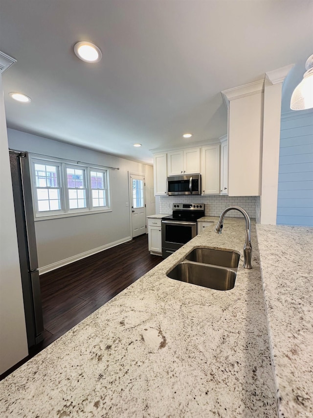 kitchen featuring light stone counters, a sink, white cabinetry, appliances with stainless steel finishes, and dark wood-style floors
