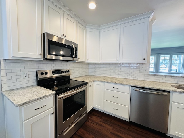 kitchen with light stone counters, decorative backsplash, dark wood-type flooring, white cabinets, and appliances with stainless steel finishes