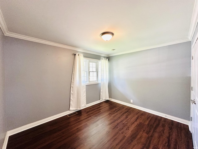 spare room with ornamental molding, baseboards, dark wood-type flooring, and visible vents