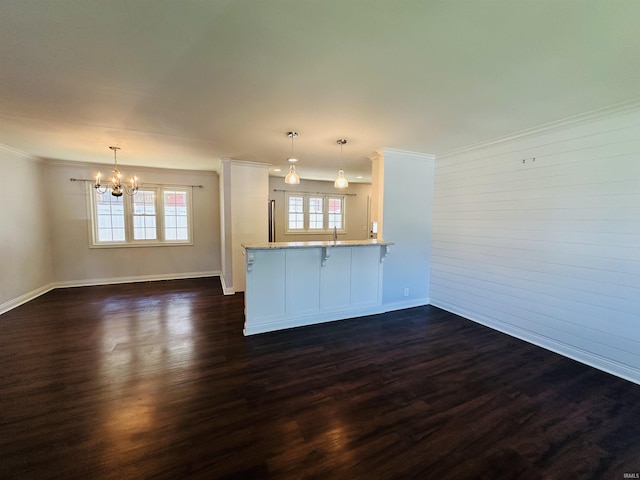 unfurnished living room with crown molding, a notable chandelier, baseboards, and dark wood-type flooring