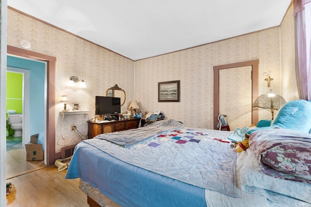 bedroom featuring wallpapered walls and wood finished floors