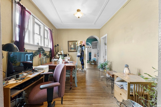 home office with arched walkways and light wood-type flooring