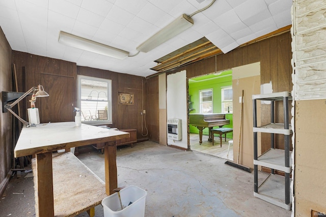 dining space with heating unit, wooden walls, and unfinished concrete flooring