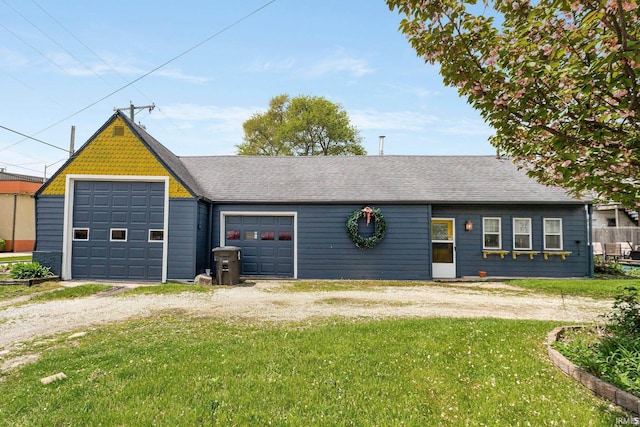 view of front facade with dirt driveway, a shingled roof, a front lawn, and a garage