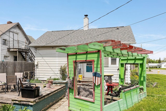 rear view of house featuring a chimney, a shingled roof, and fence