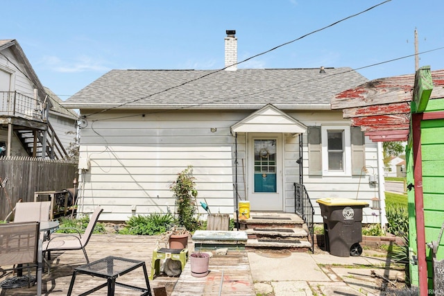 back of property featuring a chimney, outdoor dining area, fence, a patio area, and roof with shingles