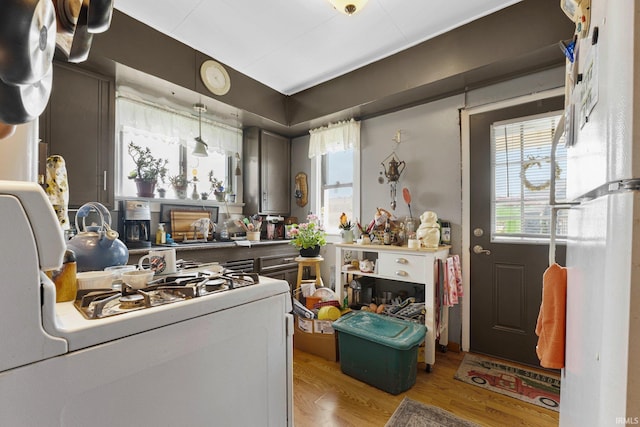 kitchen featuring range with gas stovetop, plenty of natural light, light wood-style flooring, and decorative light fixtures