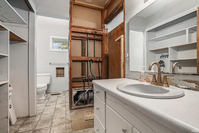 bathroom with vanity, toilet, and stone finish flooring