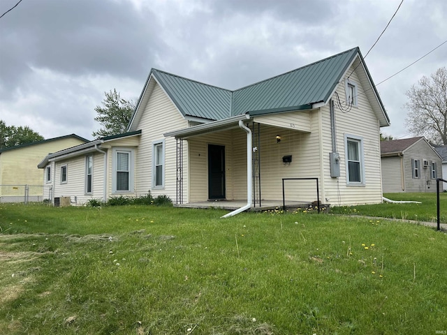 view of front of property with a porch, fence, metal roof, and a front lawn
