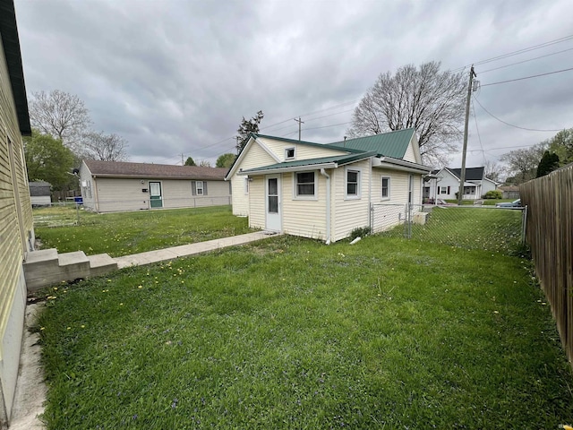 rear view of property with a yard, metal roof, and a fenced backyard