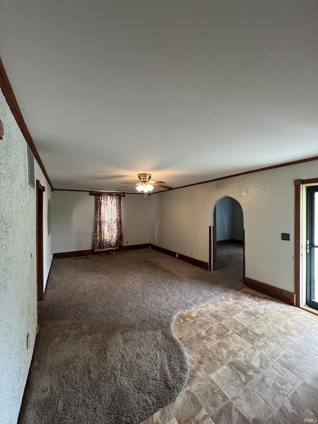 interior space featuring ceiling fan, ornamental molding, baseboards, and arched walkways