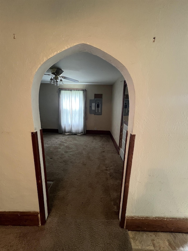 hallway featuring arched walkways, baseboards, and carpet