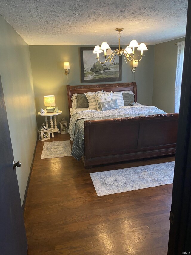 bedroom with a textured ceiling, a notable chandelier, and wood finished floors