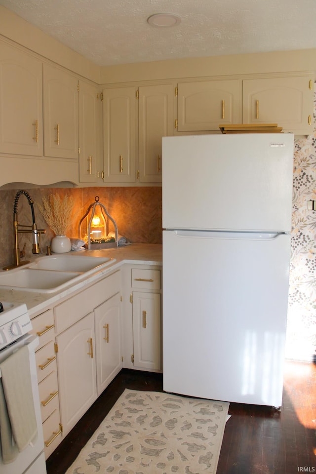 kitchen with freestanding refrigerator, light countertops, dark wood finished floors, and a sink
