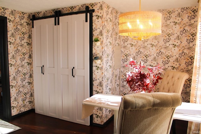 dining space featuring baseboards, a barn door, wallpapered walls, and dark wood-style floors
