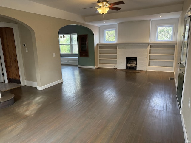 408 N 8th St, Petersburg, IN 47567 - unfurnished living room featuring baseboards, ceiling fan, arched walkways, a fireplace, and wood finished floors