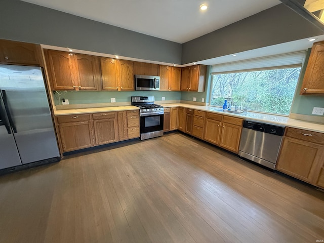408 N 8th St, Petersburg, IN 47567 - kitchen with appliances with stainless steel finishes, light countertops, wood finished floors, brown cabinetry, and a sink