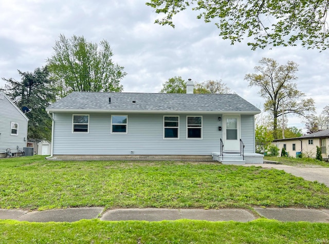 view of front of house with central AC unit, roof with shingles, a chimney, and a front yard