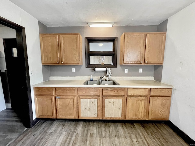 kitchen featuring light wood finished floors, light countertops, light brown cabinets, and a sink