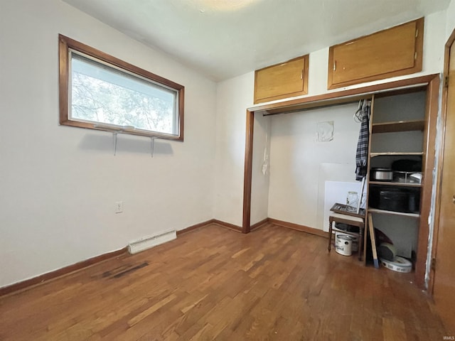 unfurnished bedroom featuring baseboards, a closet, visible vents, and wood finished floors