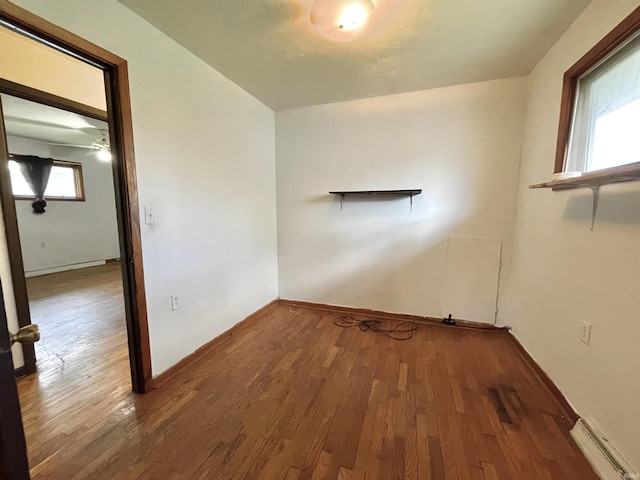 spare room with a baseboard heating unit, baseboards, and wood finished floors