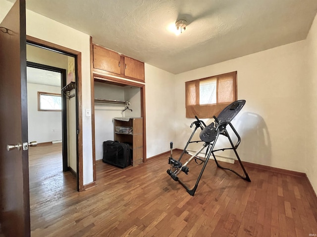 exercise room with wood finished floors and baseboards