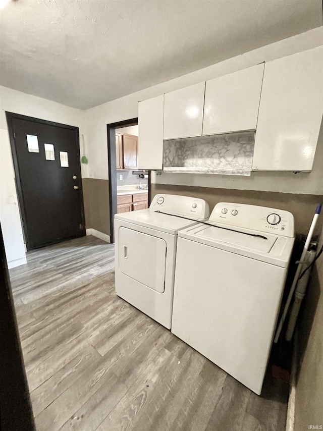 laundry area featuring cabinet space, baseboards, independent washer and dryer, and light wood-style floors