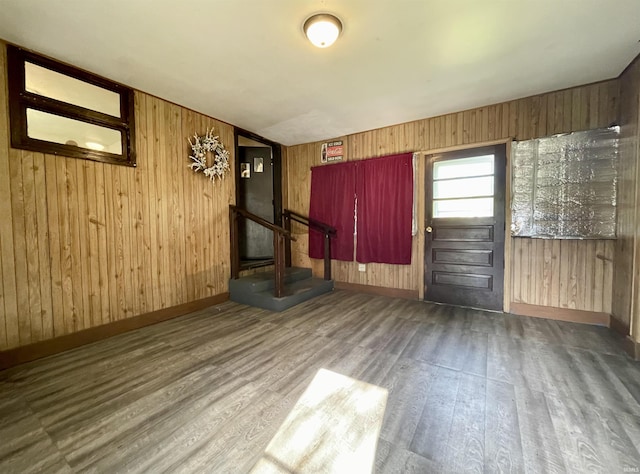 interior space featuring wooden walls, wood finished floors, baseboards, and stairway