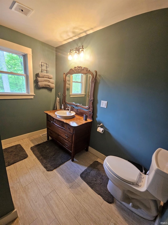 bathroom featuring toilet, wood finished floors, visible vents, baseboards, and vanity