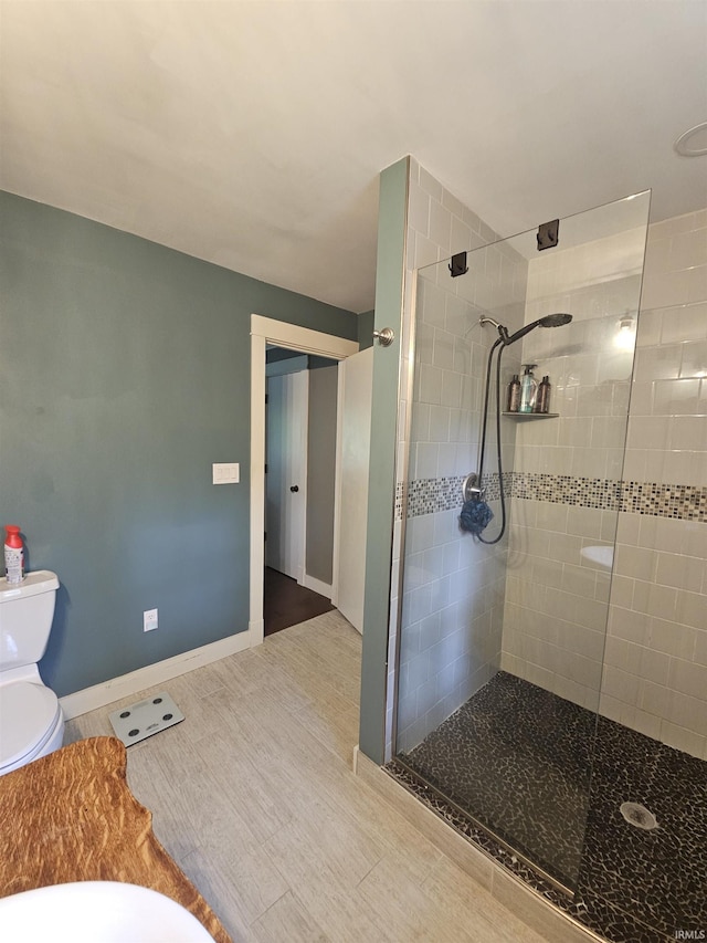 bathroom featuring toilet, wood finished floors, and tiled shower