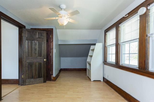 hallway with lofted ceiling, light wood-style flooring, and baseboards
