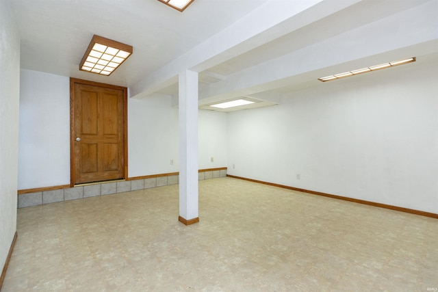 finished below grade area with baseboards and tile patterned floors
